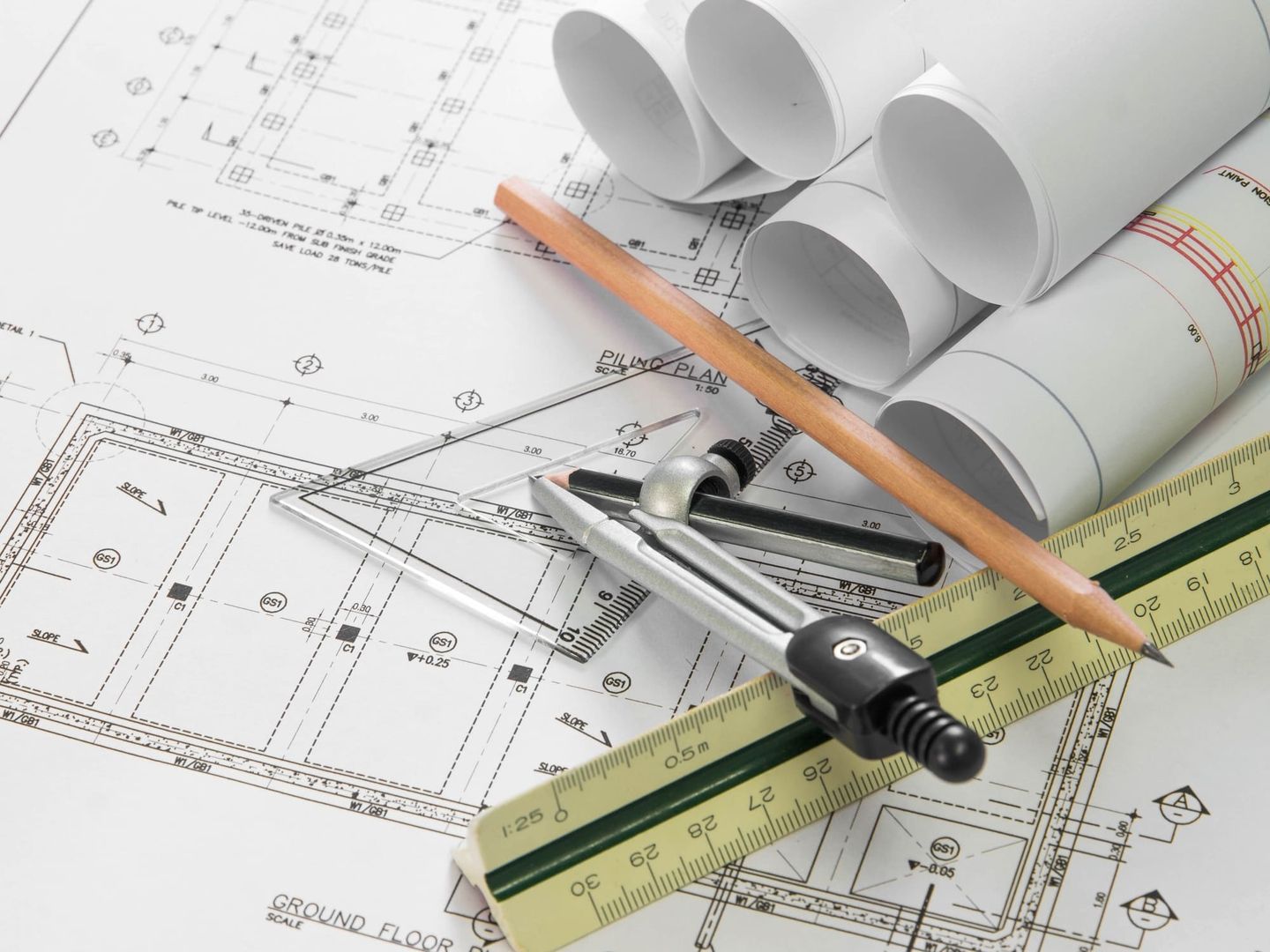 Architektonische Zeichnungen und Werkzeuge liegen auf einem Bauplan